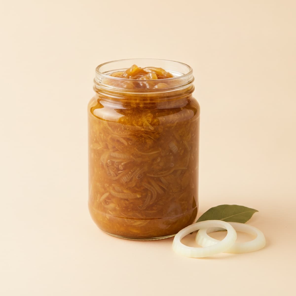 Jar of golden slow cooked onion sauce with onion rings beside it
